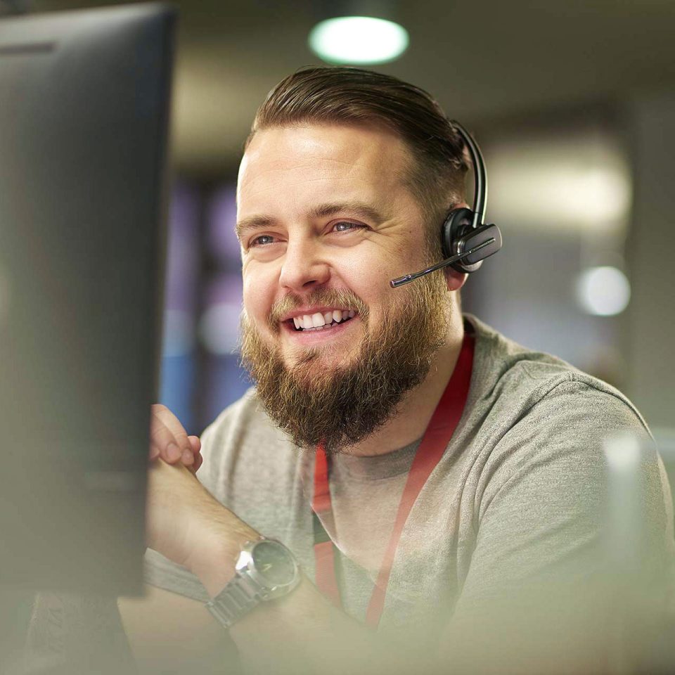 young man with headset provides IT help desk support at computer