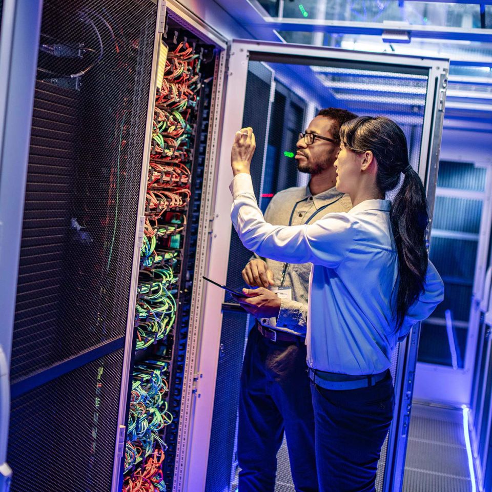 IT engineers checking cables of servers in server room